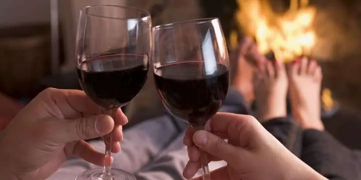 feet-warming-at-fireplace-with-hands-holding-wine