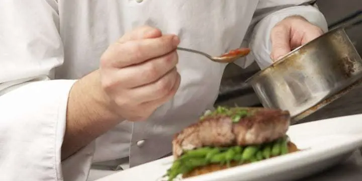 chef-adding-sauce-to-dish-in-restaurant-kitchen