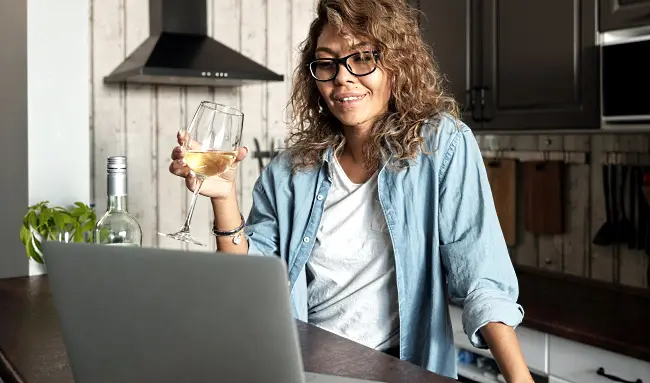 online-vinprovning-samma-tjej-i-köket-framför-datorn-med-ett-glas-vin